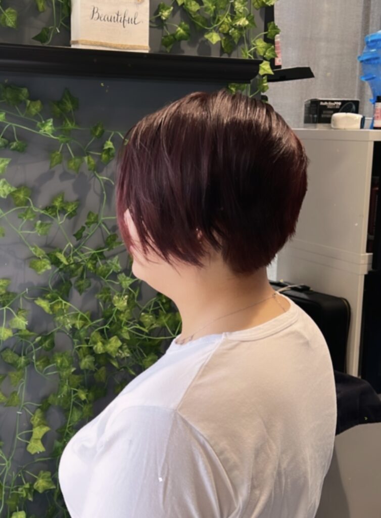 Dyed red hair in a bob reflects Ayda Ghaffari's skill at hair coloring, styling, and shaping. The hair's shorter length reflects her attention to detail and commitment to helping clients find the shape that fits their face best.