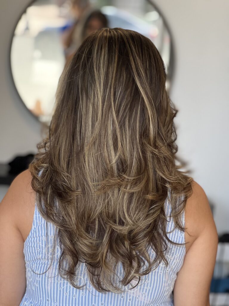 Highlighted shoulder length hair reflects Ayda Ghaffari's skill at hair coloring and styling. The hair's layering reflects her attention to detail and skill.